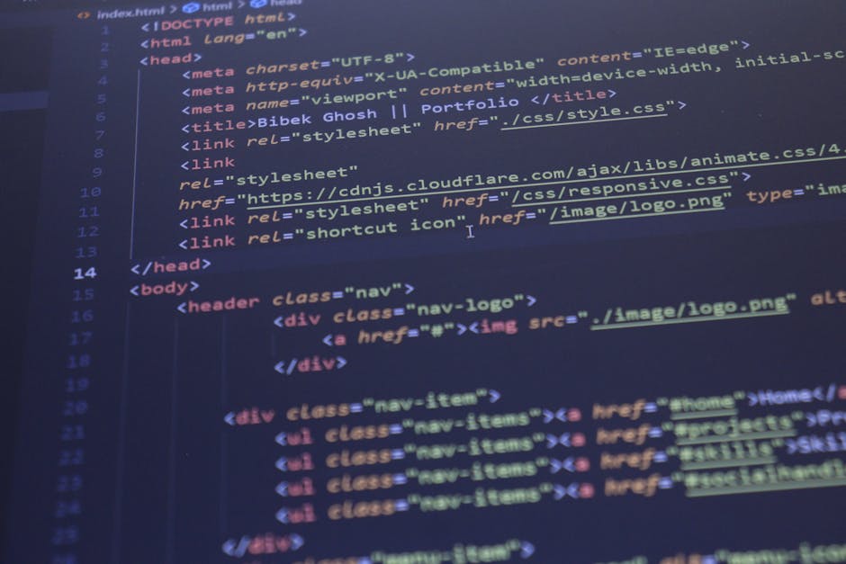 A person using a laptop computer at a dark workspace or modern office environment. The laptop screen displays lines of colorful code and text, indicating active programming or software development wor